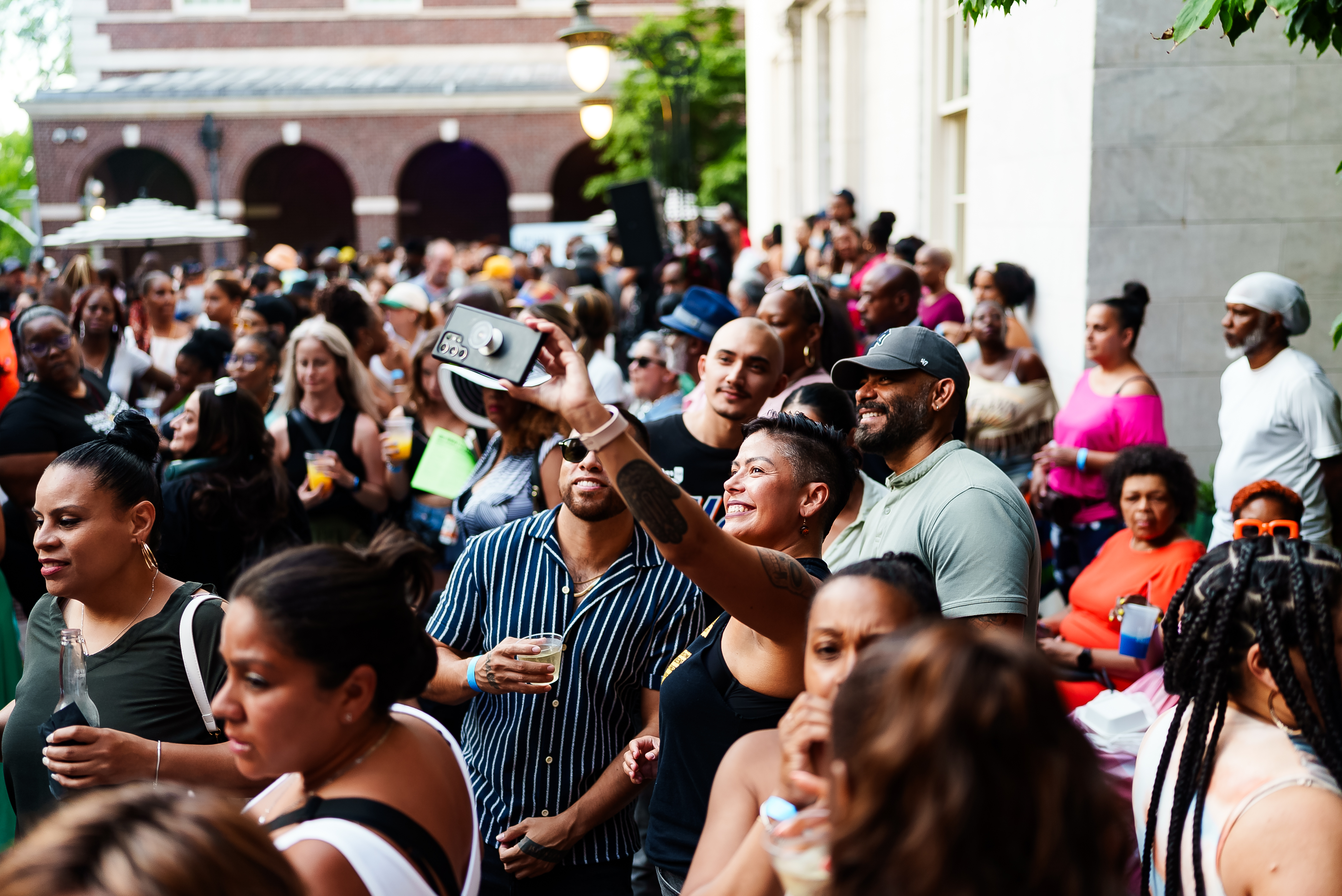 A crowd of people outside of the Museum of the City of New York and four people taking a selfie.